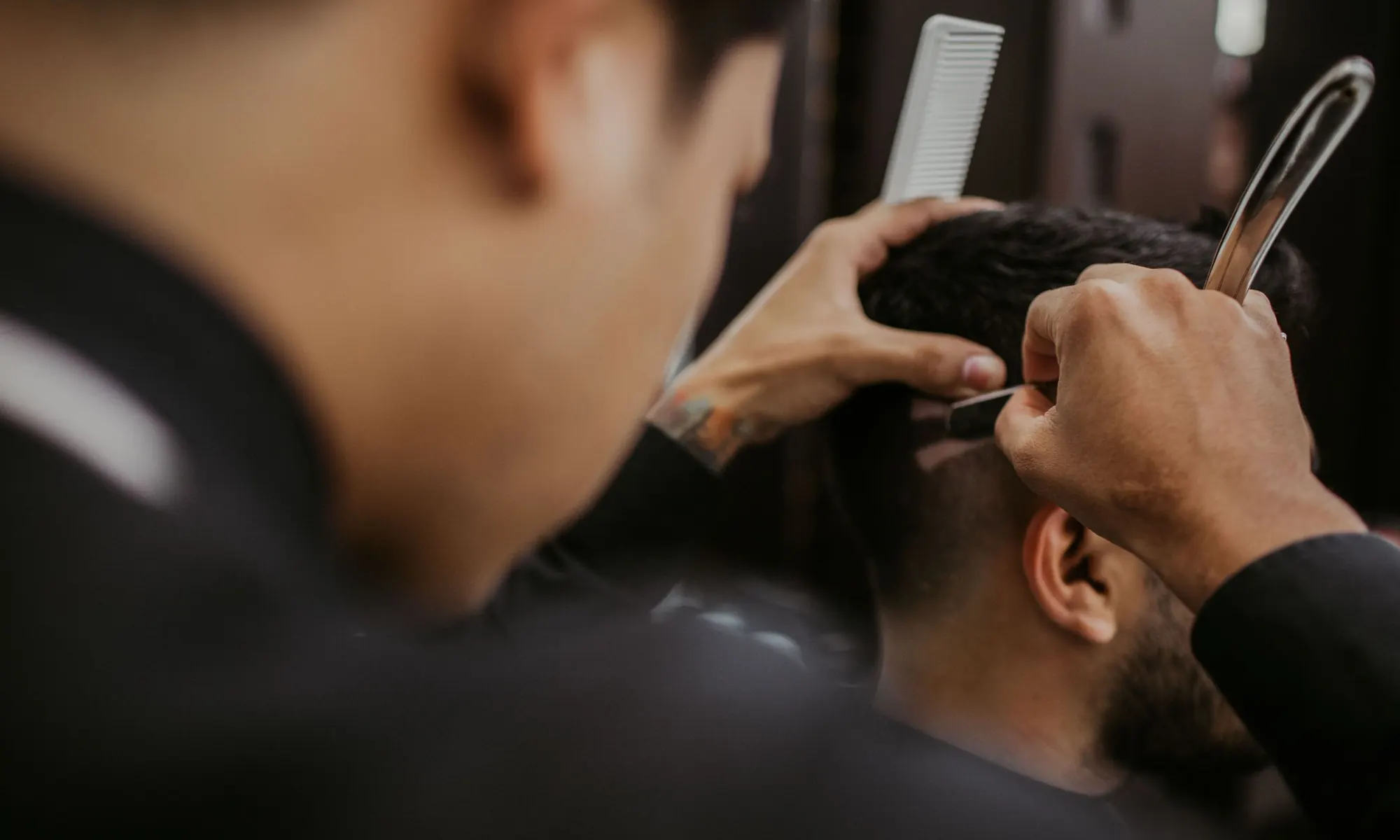 Barbier au rasoir et au peigne sur la tempe d'un client